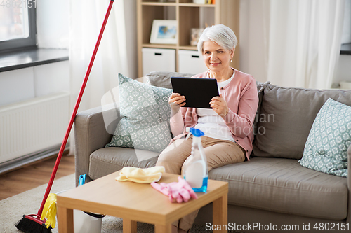 Image of senior woman using tablet pc after cleaning home