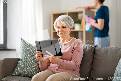 Image of old woman with tablet pc and housekeeper at home