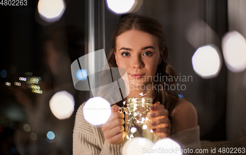 Image of woman with christmas garland lights in glass mug
