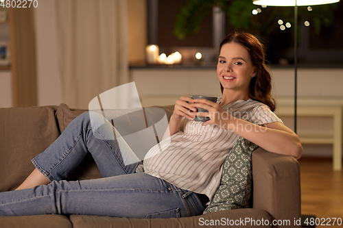 Image of smiling pregnant woman drinking tea at home