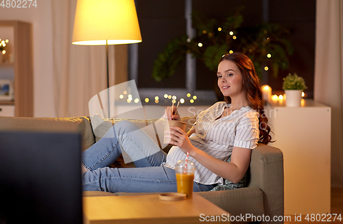 Image of pregnant woman watching tv and eating wok at home