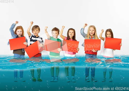Image of Group of children with blank red banners standing in water of melting glacier, global warming