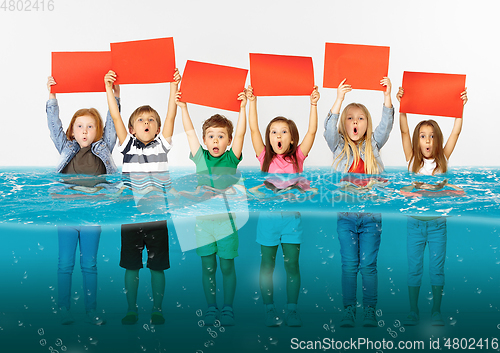 Image of Group of children with blank red banners standing in water of melting glacier, global warming