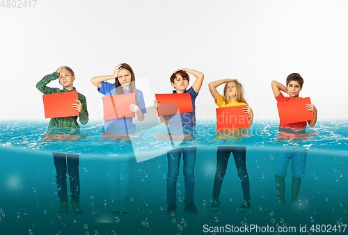 Image of Group of children with blank red banners standing in water of melting glacier, global warming