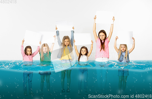 Image of Group of children with blank white banners standing in water of melting glacier, global warming