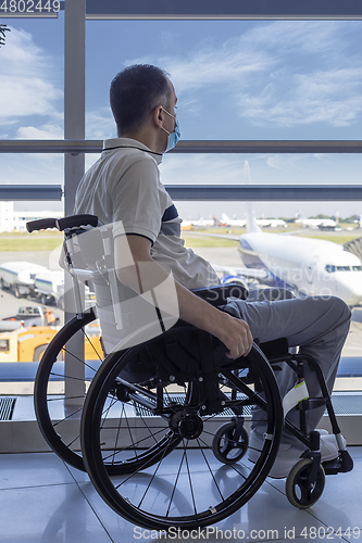 Image of Young man with protective mask in a wheelchair at the airport 