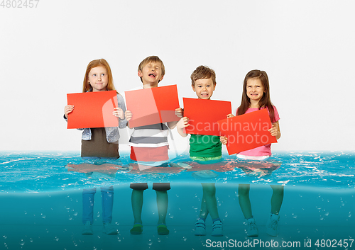 Image of Group of children with blank red banners standing in water of melting glacier, global warming