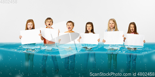 Image of Group of children with blank white banners standing in water of melting glacier, global warming