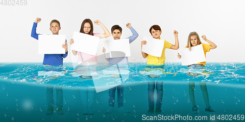 Image of Group of children with blank white banners standing in water of melting glacier, global warming