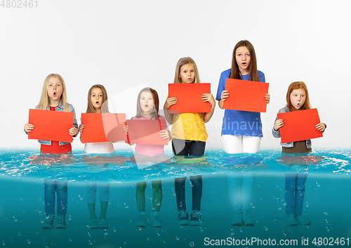 Image of Group of children with blank red banners standing in water of melting glacier, global warming