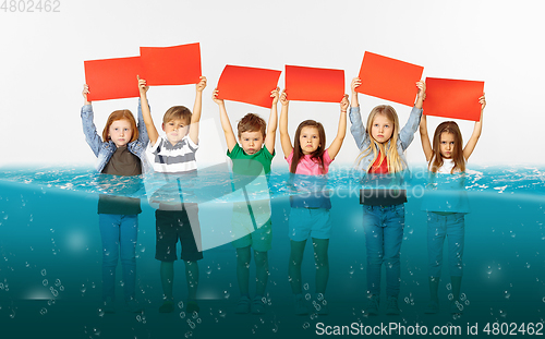 Image of Group of children with blank red banners standing in water of melting glacier, global warming