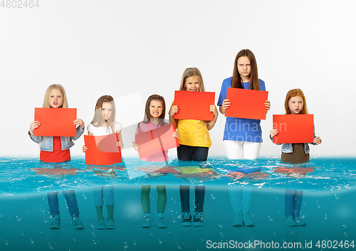 Image of Group of children with blank red banners standing in water of melting glacier, global warming