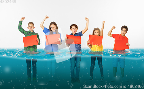 Image of Group of children with blank red banners standing in water of melting glacier, global warming