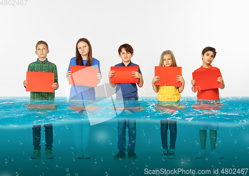 Image of Group of children with blank red banners standing in water of melting glacier, global warming