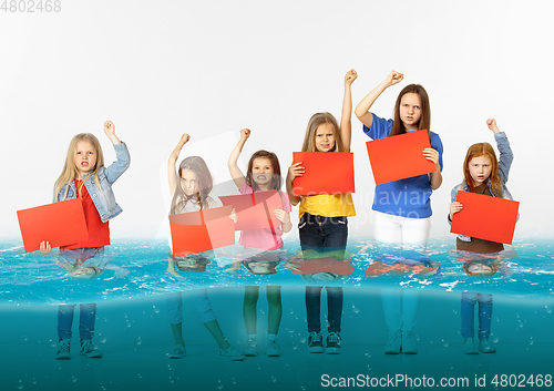Image of Group of children with blank red banners standing in water of melting glacier, global warming