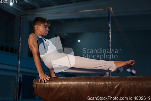 Image of Little male gymnast training in gym, flexible and active