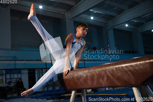 Image of Little male gymnast training in gym, flexible and active