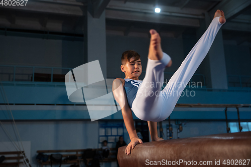 Image of Little male gymnast training in gym, flexible and active