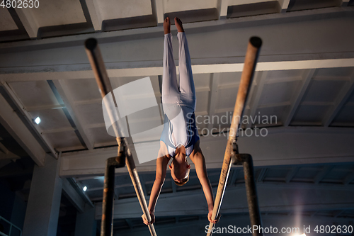 Image of Little male gymnast training in gym, flexible and active