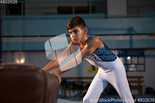 Image of Little male gymnast training in gym, flexible and active