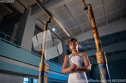 Image of Little male gymnast training in gym, flexible and active