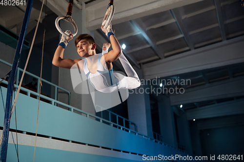 Image of Little male gymnast training in gym, flexible and active