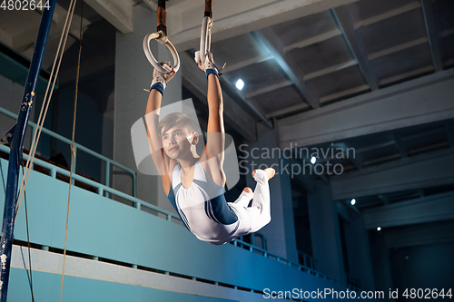 Image of Little male gymnast training in gym, flexible and active