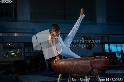 Image of Little male gymnast training in gym, flexible and active