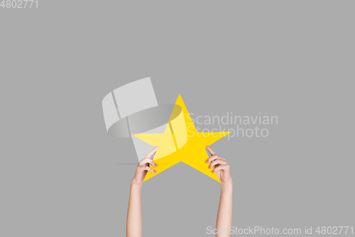 Image of Hands holding the sign of star on grey studio background