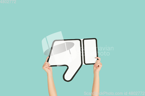 Image of Hands holding the sign of dislike on blue studio background