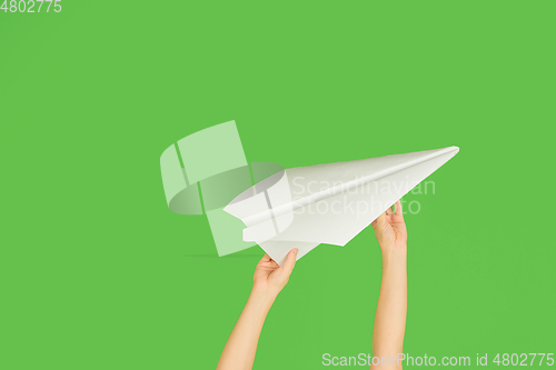 Image of Hands holding the sign of paper airplane on green studio background