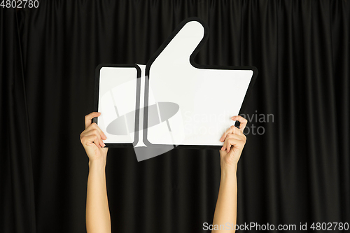 Image of Hands holding the sign of like on black studio background