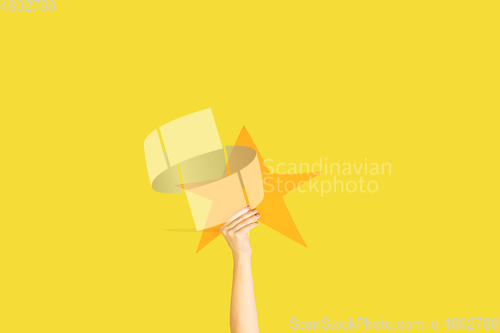 Image of Hands holding the sign of star on yellow studio background