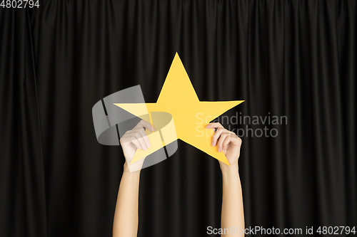 Image of Hands holding the sign of star on black studio background