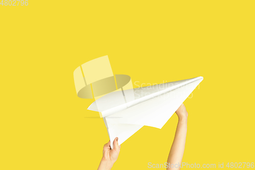 Image of Hands holding the sign of paper airplane on yellow studio background