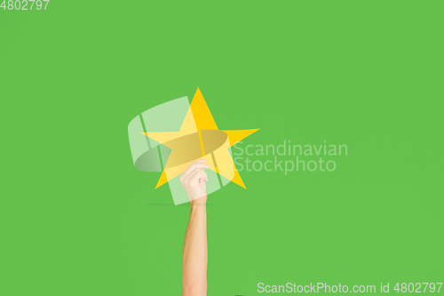 Image of Hands holding the sign of star on green studio background