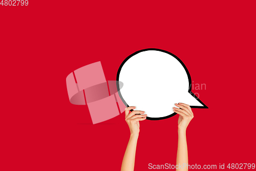 Image of Hands holding the sign of comment on red studio background