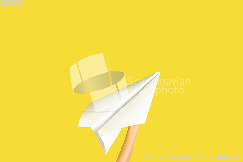 Image of Hands holding the sign of paper airplane on yellow studio background