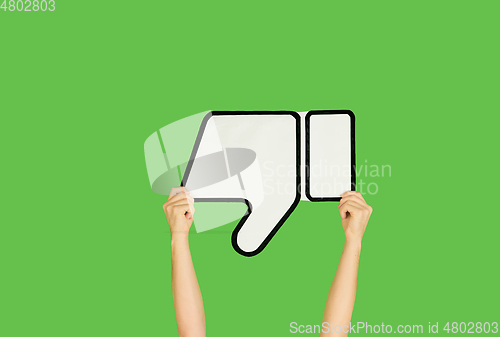 Image of Hands holding the sign of dislike on green studio background