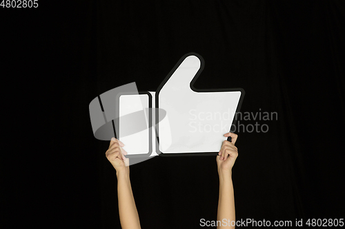 Image of Hands holding the sign of like on black studio background