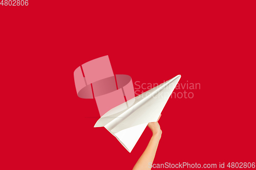 Image of Hands holding the sign of paper airplane on red studio background