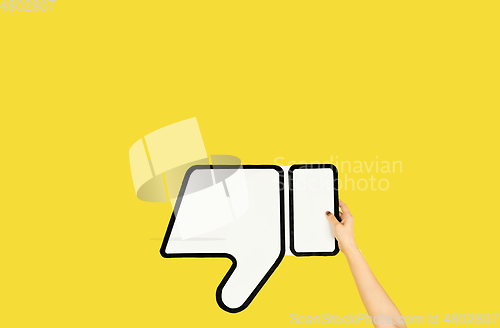 Image of Hands holding the sign of dislike on yellow studio background