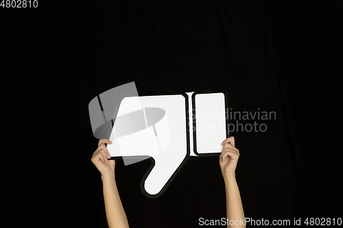 Image of Hands holding the sign of dislike on black studio background