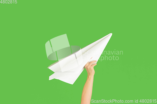 Image of Hands holding the sign of paper airplane on green studio background