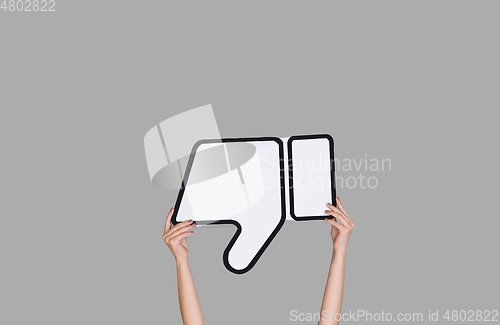 Image of Hands holding the sign of dislike on grey studio background