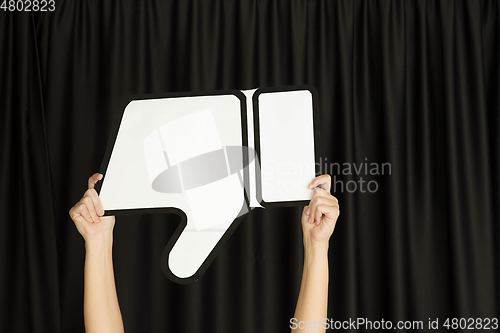 Image of Hands holding the sign of dislike on black studio background