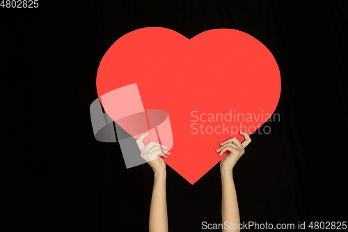 Image of Hands holding the sign of heart on black studio background