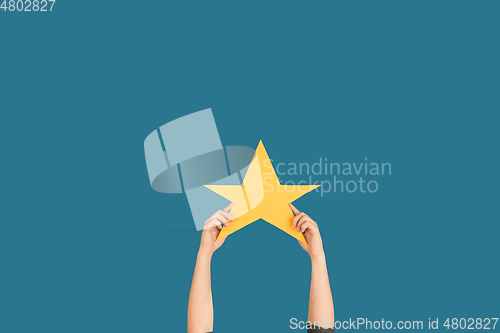 Image of Hands holding the sign of star on blue studio background