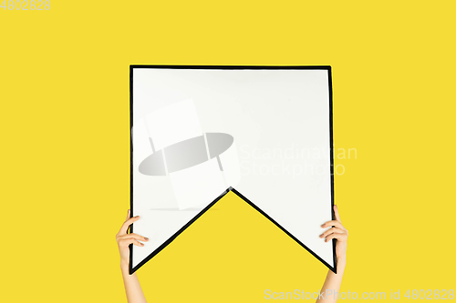 Image of Hands holding the sign of bookmark on yellow studio background