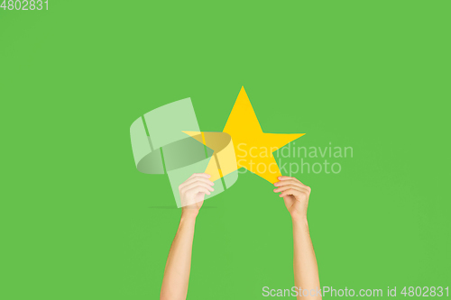 Image of Hands holding the sign of star on green studio background
